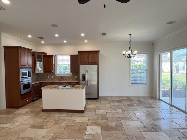 kitchen with light stone counters, ornamental molding, tasteful backsplash, a kitchen island with sink, and appliances with stainless steel finishes