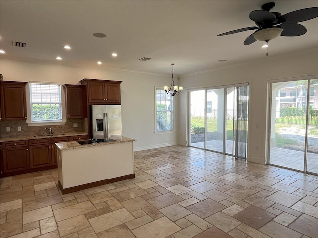 kitchen featuring a healthy amount of sunlight, backsplash, stainless steel fridge with ice dispenser, and a kitchen island