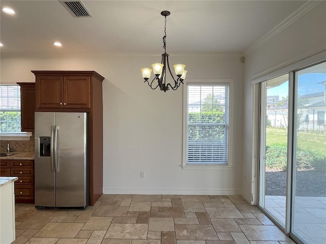 kitchen featuring hanging light fixtures, stainless steel fridge, tasteful backsplash, and a healthy amount of sunlight