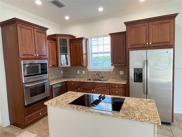 kitchen featuring appliances with stainless steel finishes, a kitchen island, light stone countertops, ornamental molding, and sink