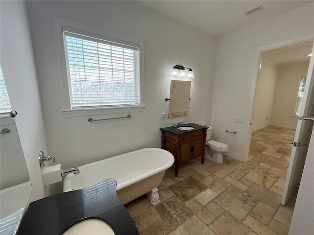 bathroom with a bath, vanity, and toilet