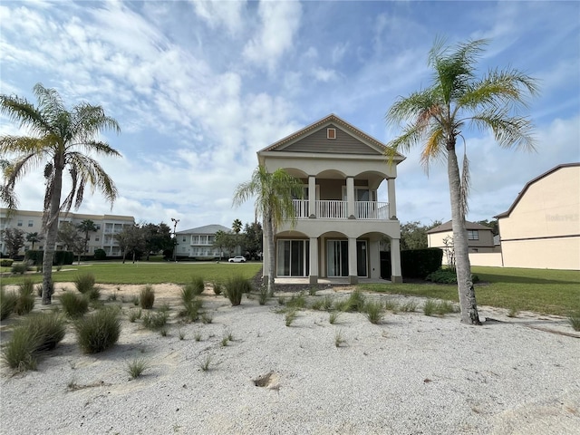 neoclassical home with a balcony and a front lawn