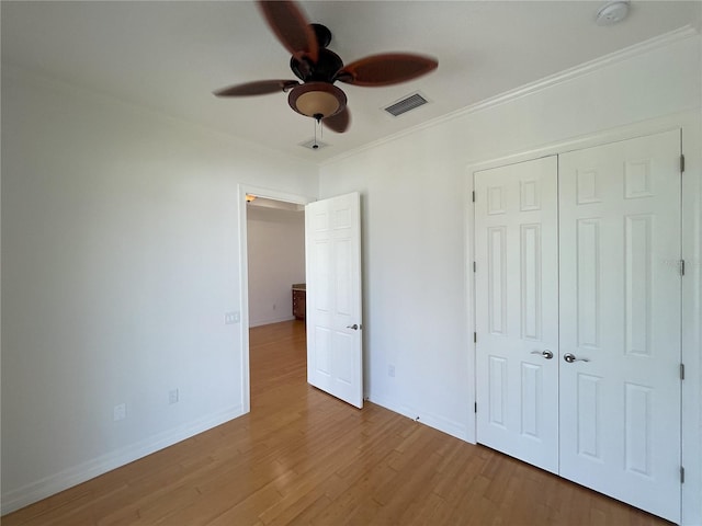 unfurnished bedroom featuring ornamental molding, ceiling fan, a closet, and light hardwood / wood-style flooring