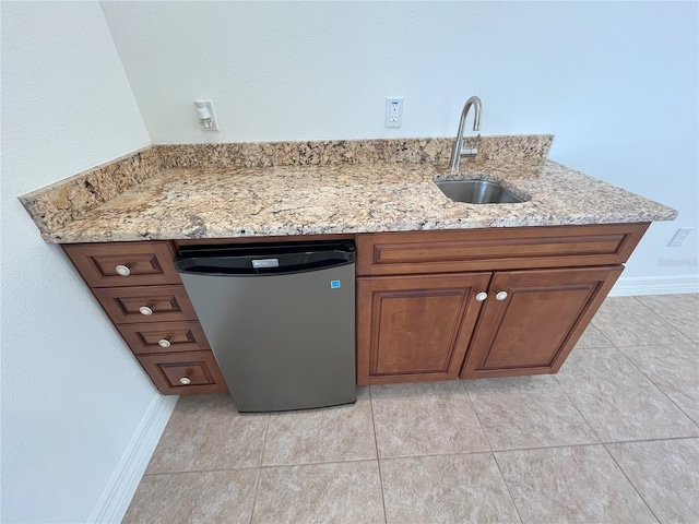 kitchen with dishwasher, light stone counters, light tile patterned flooring, and sink