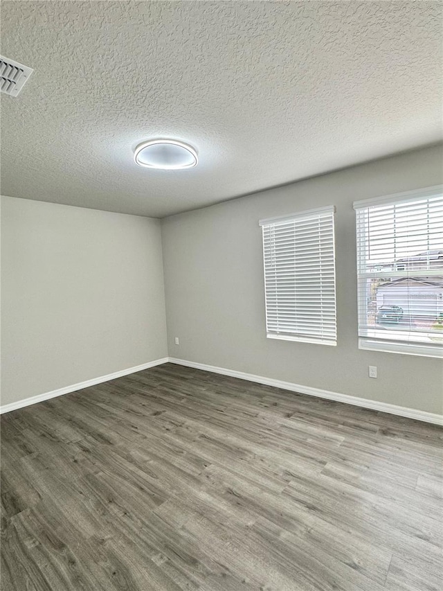 spare room featuring dark wood-type flooring and a textured ceiling