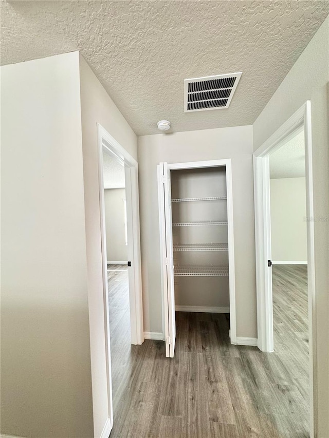 hallway featuring a textured ceiling and light wood-type flooring