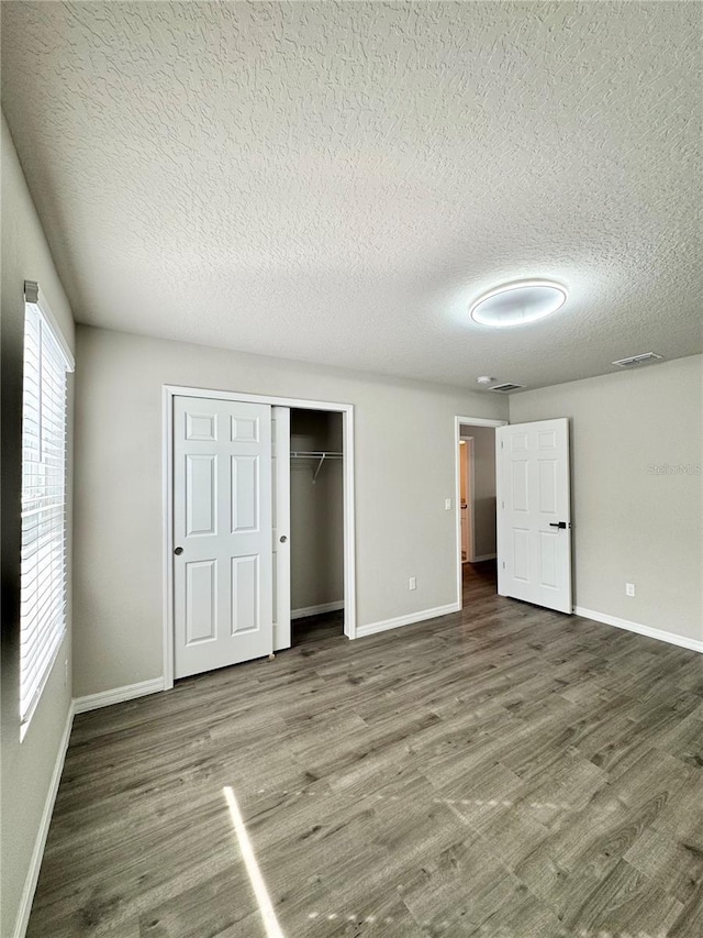 unfurnished bedroom featuring dark hardwood / wood-style flooring, a closet, and a textured ceiling