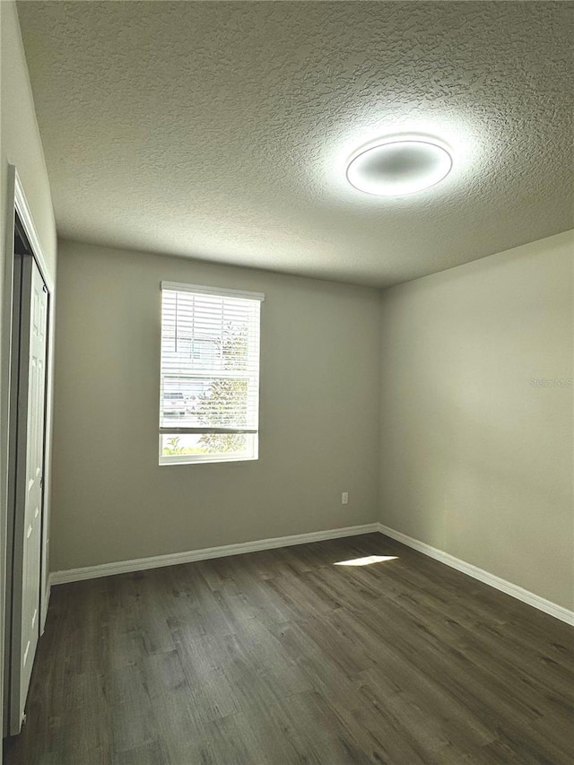 empty room with dark hardwood / wood-style flooring and a textured ceiling