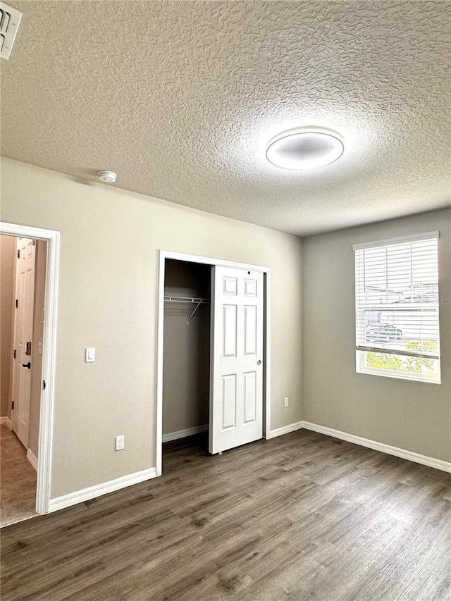 unfurnished bedroom featuring dark hardwood / wood-style flooring, a closet, and a textured ceiling