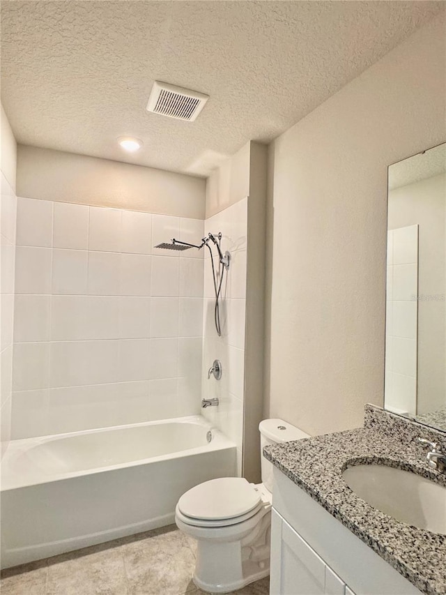 full bathroom featuring tiled shower / bath, tile patterned flooring, vanity, toilet, and a textured ceiling