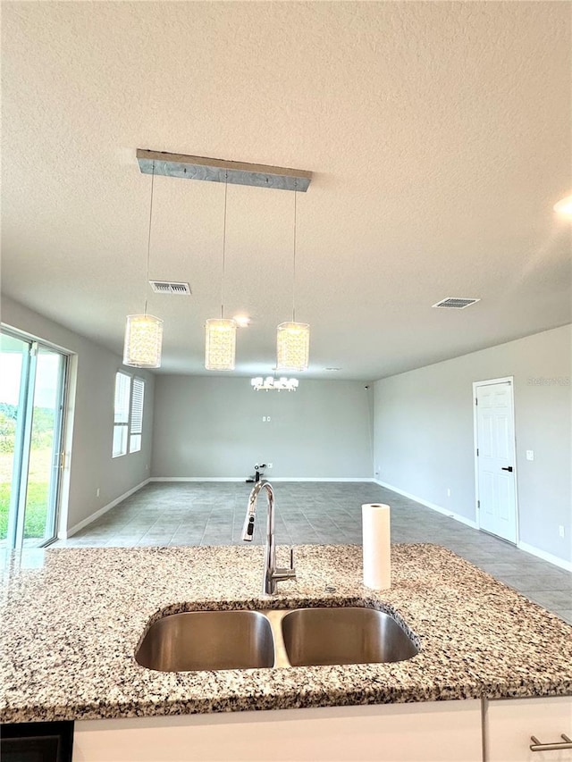 kitchen with pendant lighting, sink, and light stone countertops