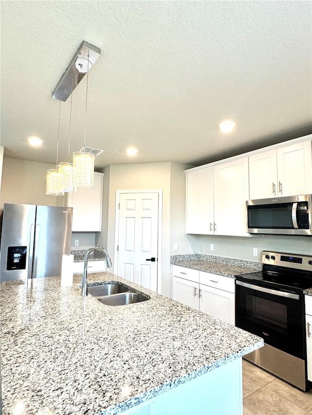 kitchen with pendant lighting, sink, white cabinets, and appliances with stainless steel finishes