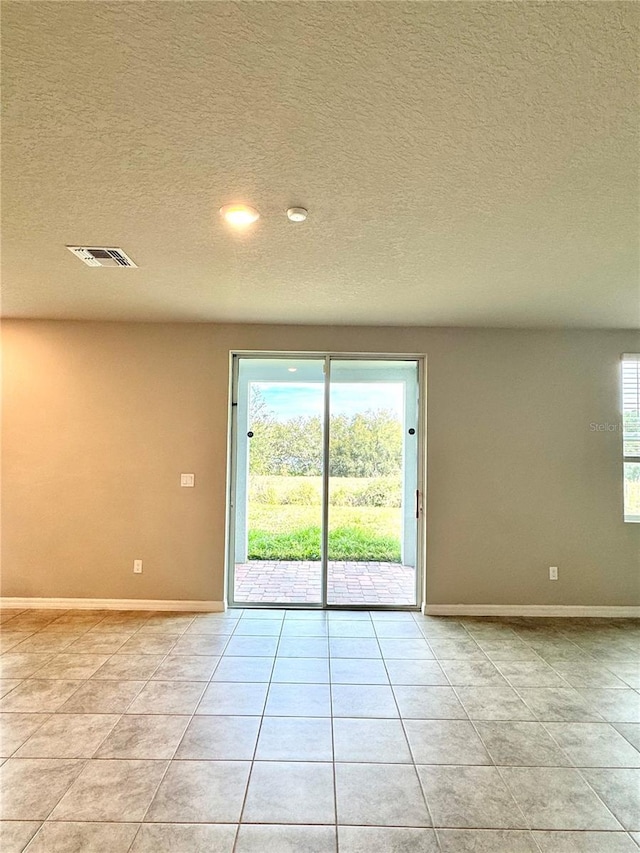 tiled empty room featuring plenty of natural light and a textured ceiling