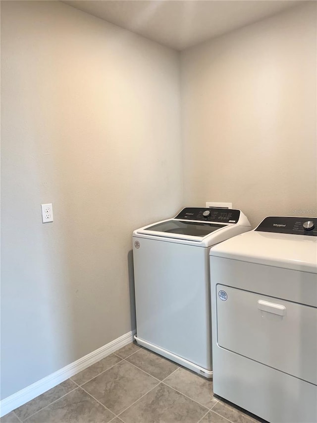 clothes washing area with light tile patterned flooring and washer and clothes dryer