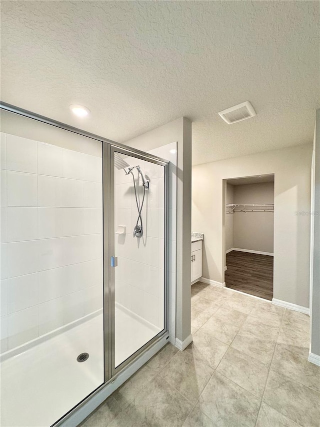 bathroom with tile patterned flooring, an enclosed shower, and a textured ceiling