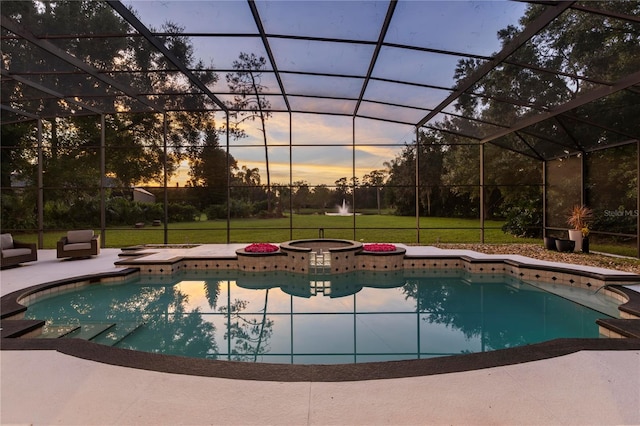 pool at dusk with an in ground hot tub, a yard, a lanai, and a patio area