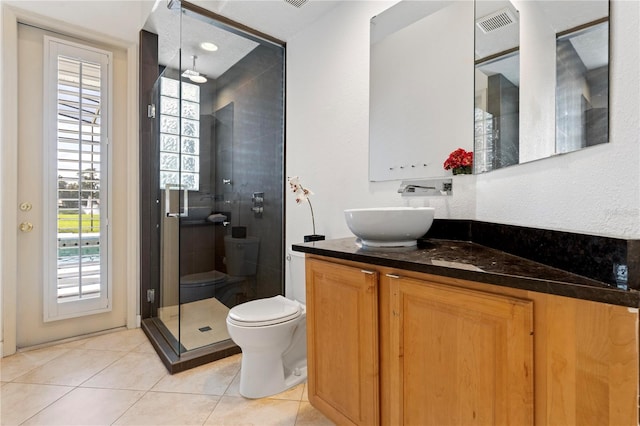 bathroom featuring vanity, tile patterned flooring, toilet, and a shower with door