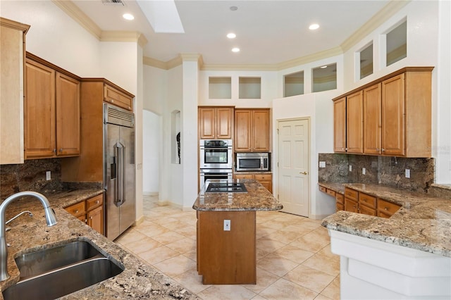 kitchen featuring light stone counters, sink, a kitchen island, stainless steel appliances, and crown molding