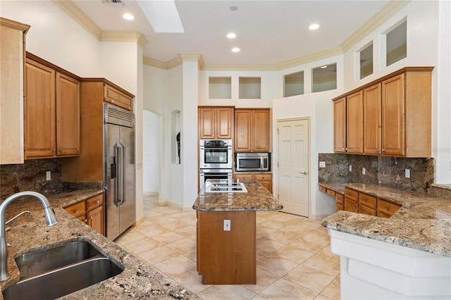 kitchen with sink, appliances with stainless steel finishes, a center island, light stone countertops, and crown molding