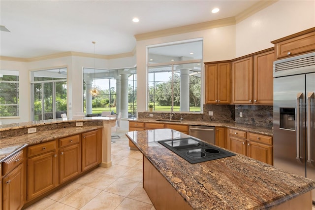 kitchen with stainless steel appliances, a center island, stone countertops, and sink