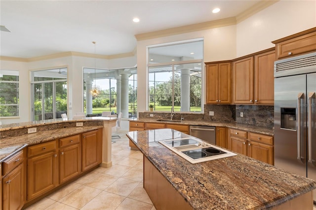 kitchen with pendant lighting, sink, a kitchen island, stainless steel appliances, and crown molding