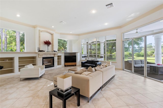 tiled living room with ceiling fan, a fireplace, and ornamental molding