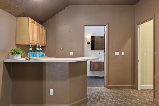 kitchen featuring a kitchen breakfast bar, lofted ceiling, kitchen peninsula, and light brown cabinetry