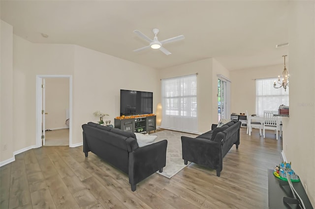 living room with ceiling fan with notable chandelier and light wood-type flooring