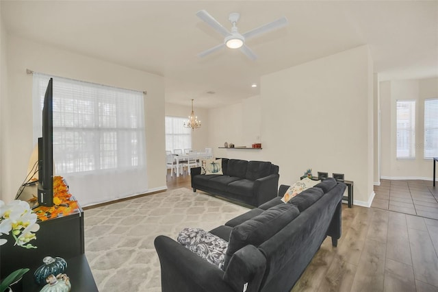 living room featuring ceiling fan with notable chandelier and light hardwood / wood-style flooring