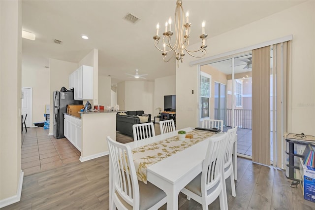 dining space featuring ceiling fan with notable chandelier and light hardwood / wood-style flooring