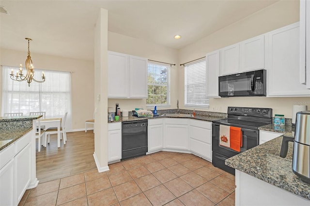 kitchen with white cabinets, light tile patterned floors, black appliances, and a notable chandelier