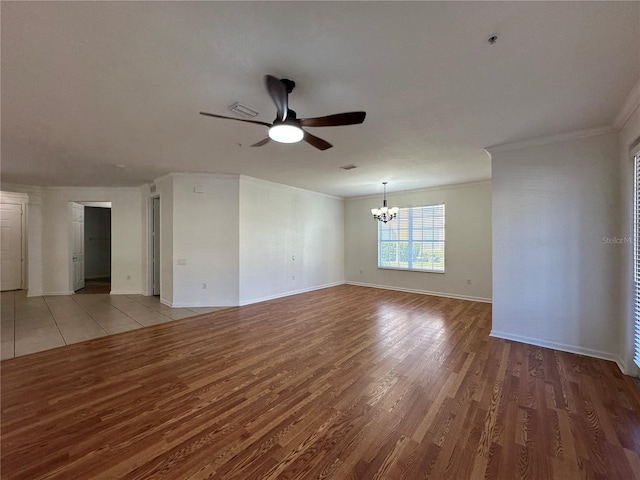 unfurnished room featuring ceiling fan with notable chandelier, wood finished floors, baseboards, and ornamental molding