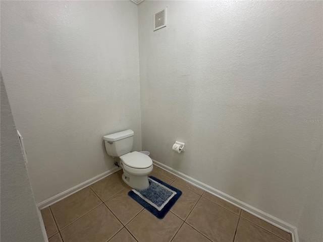 bathroom featuring tile patterned flooring, toilet, visible vents, and baseboards