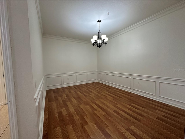 unfurnished room featuring ornamental molding, an inviting chandelier, and wood finished floors