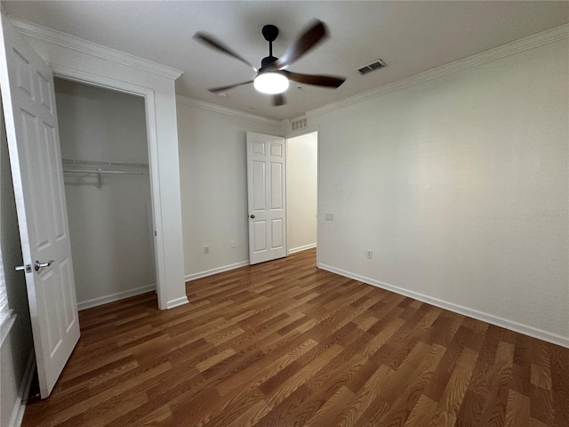 unfurnished bedroom with visible vents, crown molding, baseboards, wood finished floors, and a closet