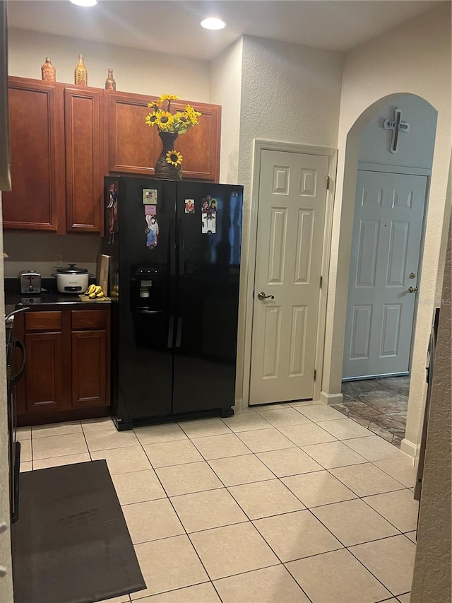 kitchen with black fridge with ice dispenser and light tile patterned floors