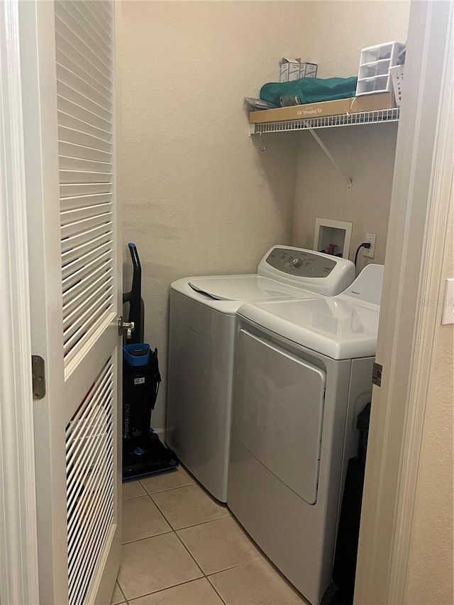 clothes washing area featuring light tile patterned floors and washing machine and clothes dryer