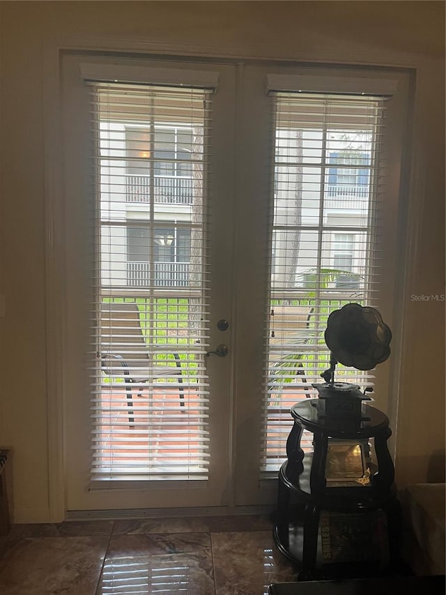 doorway to outside with dark tile patterned flooring and plenty of natural light