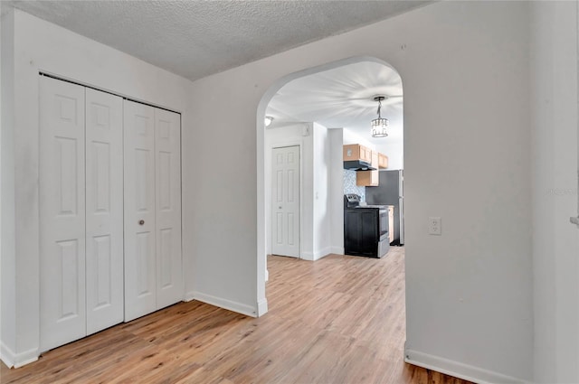 hallway with light hardwood / wood-style flooring and a textured ceiling