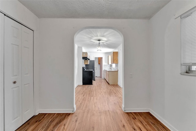 corridor featuring a textured ceiling and light hardwood / wood-style floors