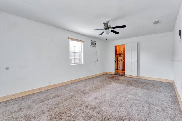 spare room with ceiling fan, electric water heater, carpet, and a wall unit AC