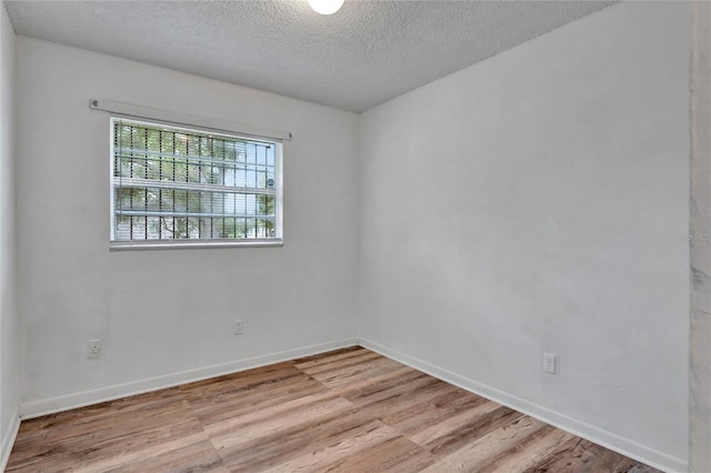 empty room featuring a textured ceiling and light hardwood / wood-style flooring