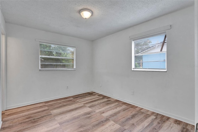 spare room featuring light wood-type flooring and a textured ceiling