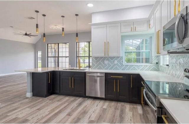 kitchen with white cabinets, appliances with stainless steel finishes, hanging light fixtures, and a wealth of natural light