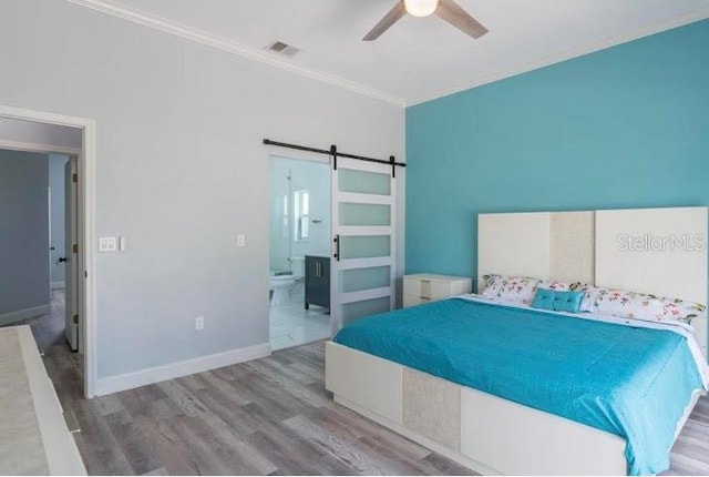 bedroom with ceiling fan, ornamental molding, hardwood / wood-style flooring, and a barn door