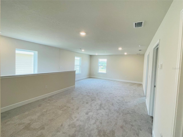 unfurnished room with light carpet and a textured ceiling