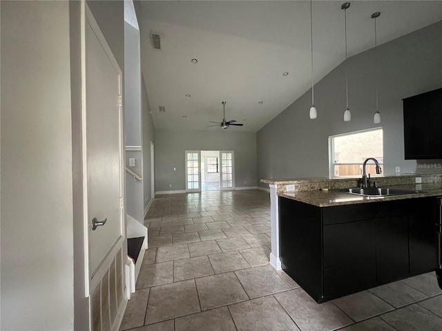 kitchen with ceiling fan, light stone counters, light tile patterned flooring, sink, and high vaulted ceiling