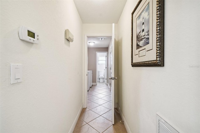 hallway with a textured ceiling and light tile patterned floors