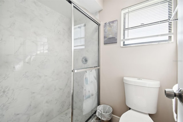 bathroom featuring a shower with door and toilet