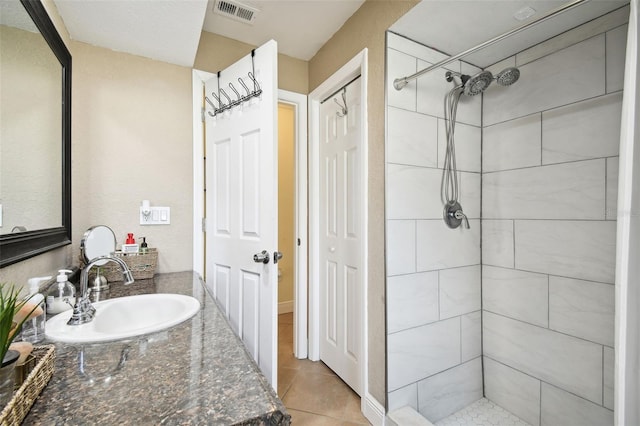 bathroom featuring a tile shower, tile patterned flooring, and vanity